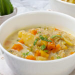 Quinoa soup, freshly made, served in a white bowl.