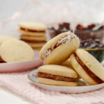 Freshly baked alfajores with coconut edges on a serving plate