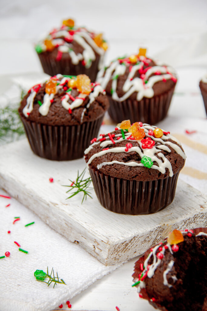 Close-up of Christmas Chocolate Muffins showing a rich chocolate texture with candied orange peel and sprinkled holiday decorations.