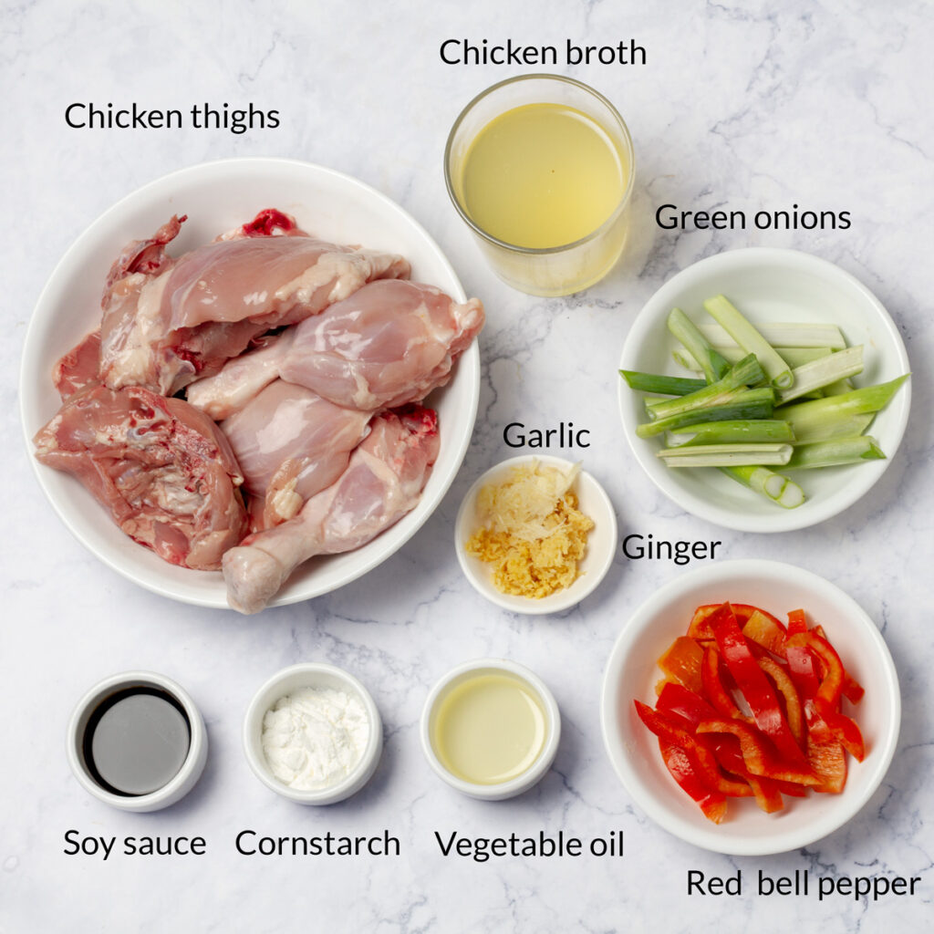 Ingredients for Pollo al Sillao: A display of ingredients for Peruvian chicken in sillao sauce, including ginger root, soy sauce, garlic, and sliced green onions on a cutting board.