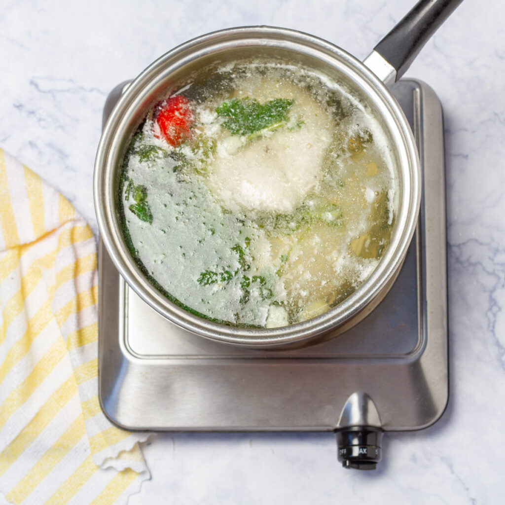 Boiling chicken breast with aromatic vegetables for Ensalada de Gallina.