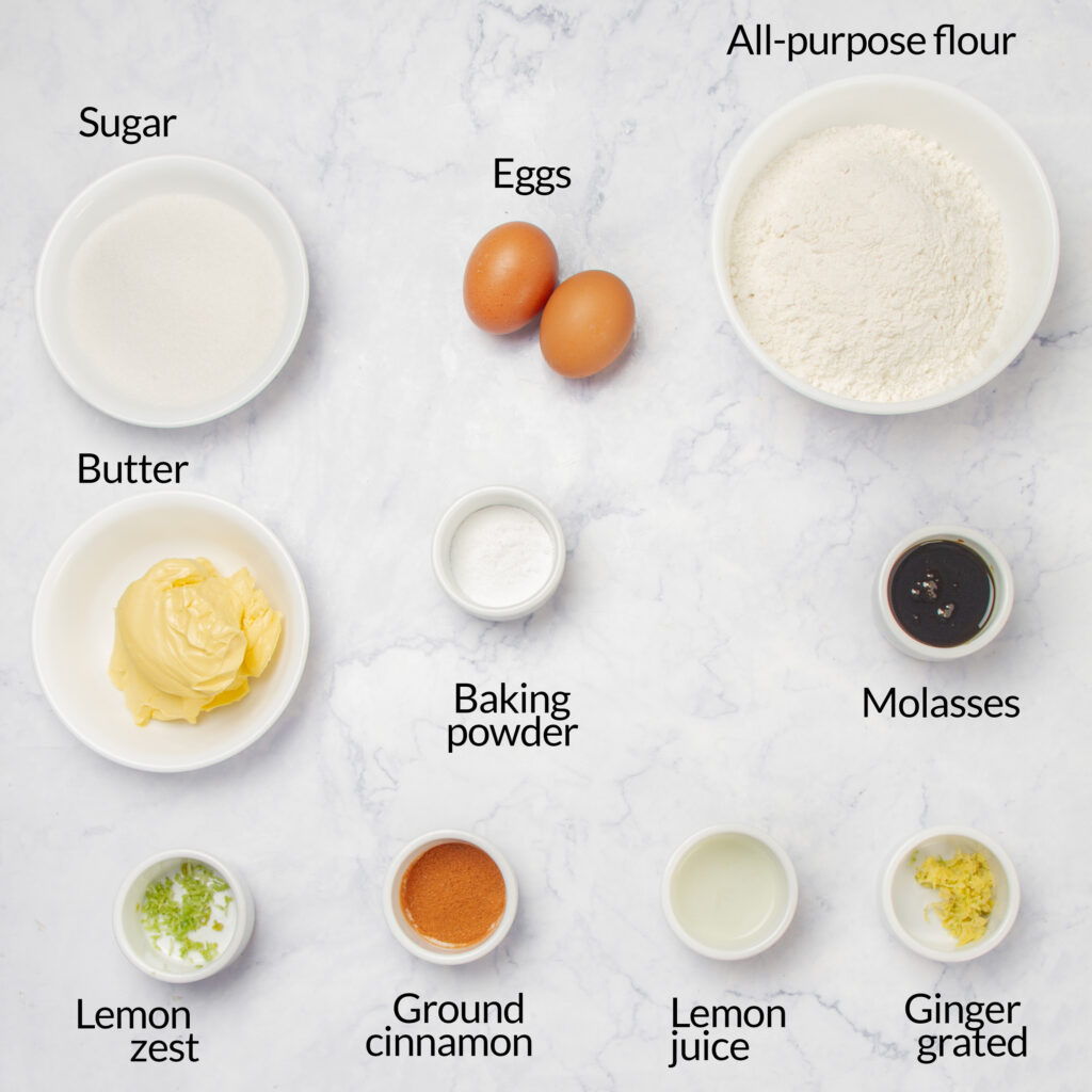 A collection of baking ingredients for making classic, crackled gingerbread cookies, including flour, sugar, eggs, butter, and spices.