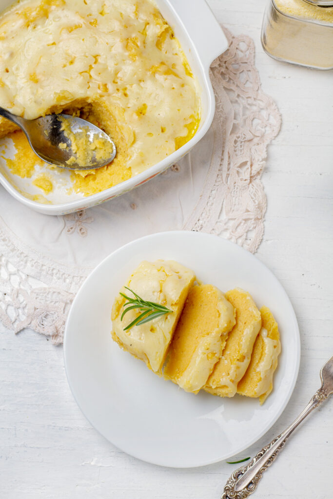 A top-down view of a golden-brown polenta dish, sliced and topped with melted cheese.