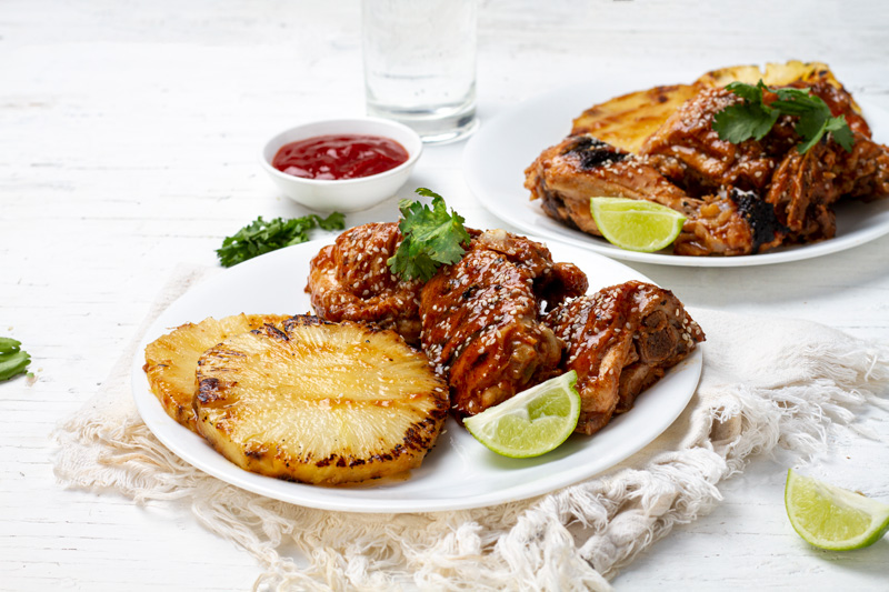 A sizzling plate of Huli Huli chicken and grilled pineapple, marinated in a sweet and savory sauce. The perfect dish for a Hawaiian-themed barbecue.