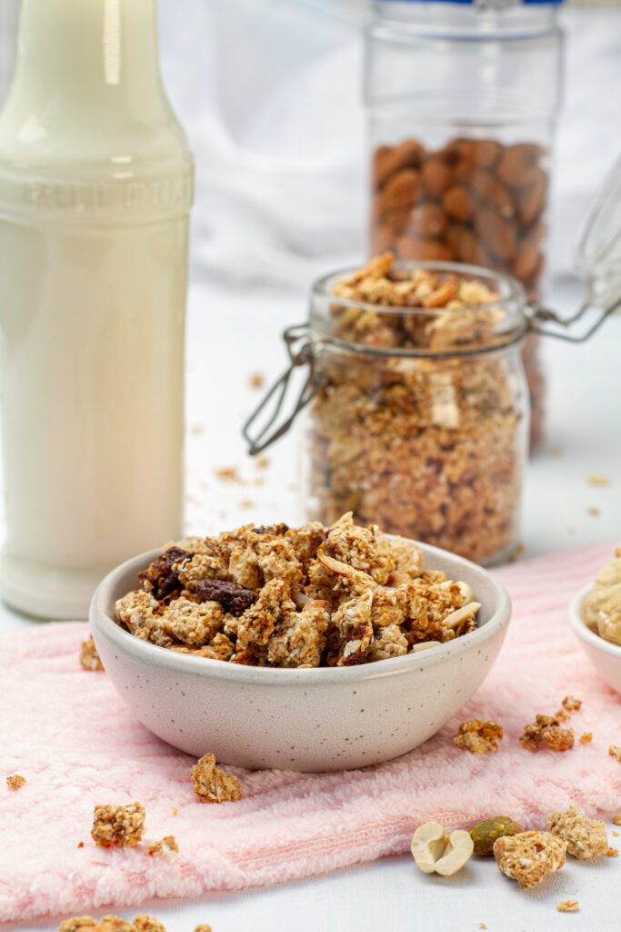 A close-up of a bowl of granola with various nuts and seeds on a white surface.