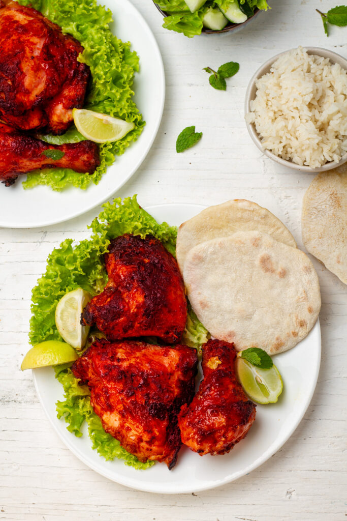  A plate of juicy tandoori chicken served with rice, naan bread, and a side salad.